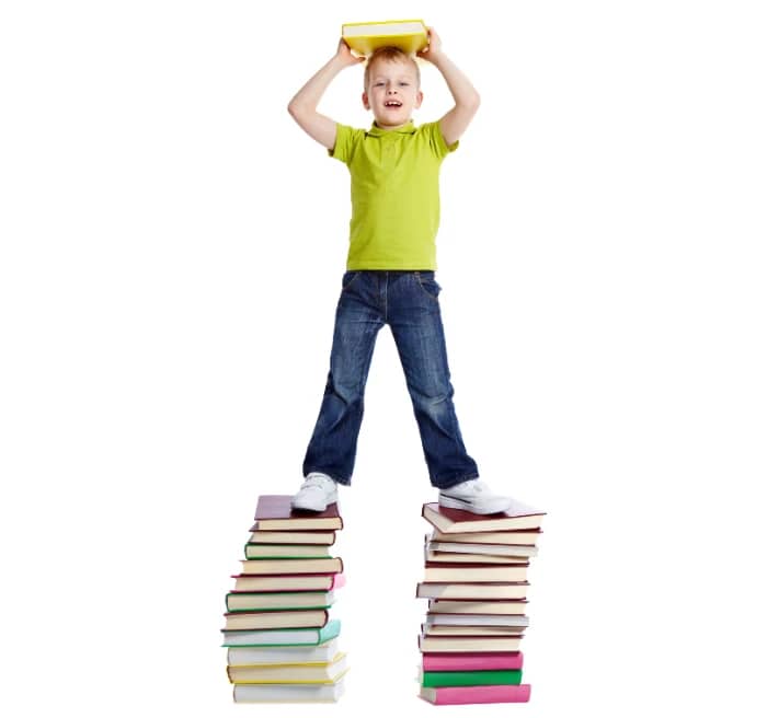 Niño se apoya en dos pilas de libros como si fueran los hombros de gigantes Cambridge y Oxford de los cursos de inglés para niños de Walken School